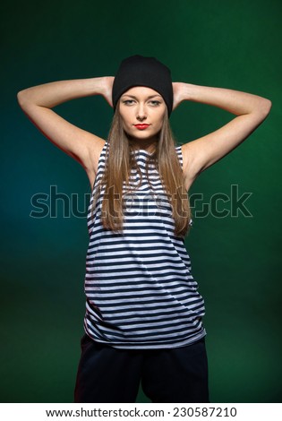 Portrait of a young woman hip hop dancer is looking at the camera, on the colored background.