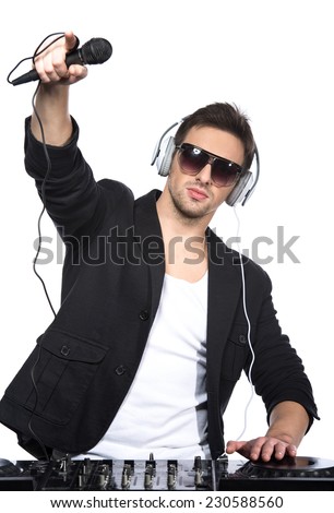 Portrait of a young DJ standing at the mixer on a light background.