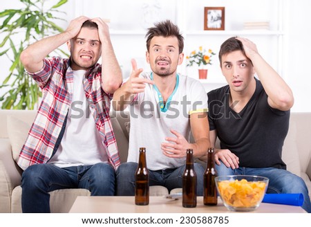 Group of sports fans watching game on TV at home.
