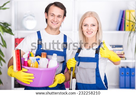 Young smiling couple are holding cleaning tools.