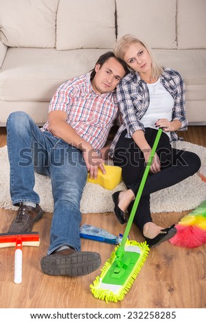 Young couple are sitting on the floor with cleaning products. Tired.