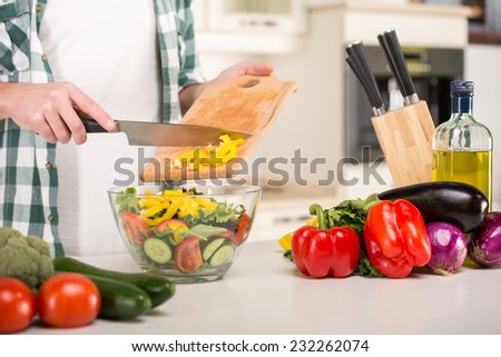 Hands of man is cooking vegetable salad in the kitchen.
