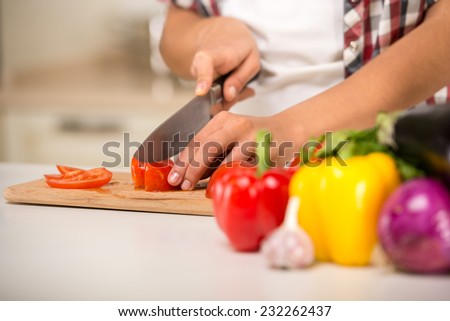 Close-up hands of a woman who cuts vegetables. Focus on the vegetables on the table.