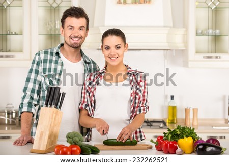 Smiling woman and  husband are cooking with fresh vegetables.