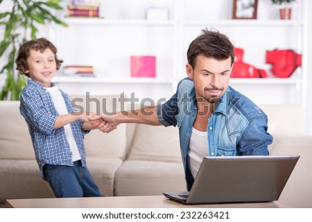 Son wants to spend time with his dad. Father is busy with work in computer.