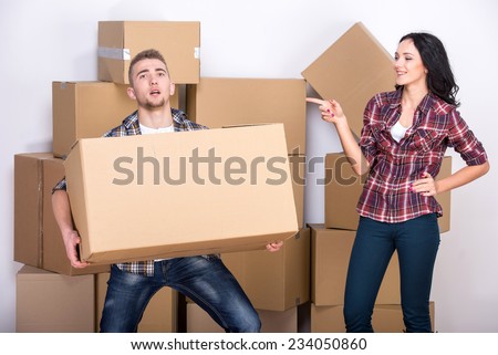 Moving to a new apartment. Young man picked up a heavy box, woman laughing.