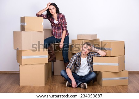 Tired couple with boxes are moving into new apartment.