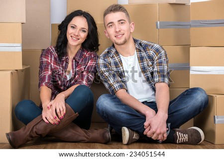 Happy young couple are moving in new home. Man and woman are sitting on the floor.