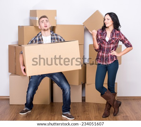 Moving to a new apartment. Young man picked up a heavy box, woman laughing.