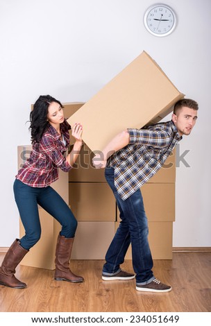 Young woman helps her husband to lift a box.