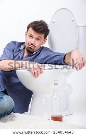 Drunk man with wine bottle in toilet, isolated on white.