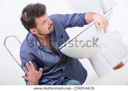 Drunk man with wine bottle in toilet, isolated on white.
