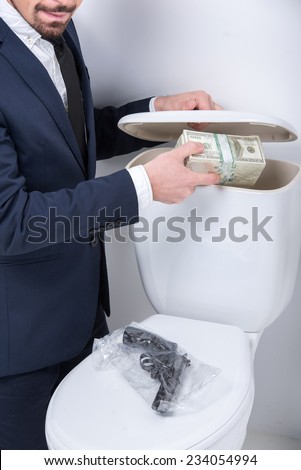 Young man pulls gun and money from the toilet tank.