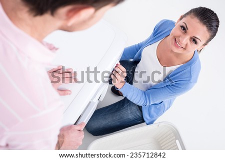Housework. Young woman and man are doing laundry with washing machine at home.