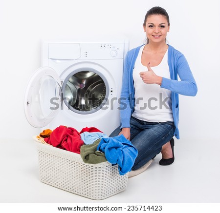 Happy young woman is doing laundry with washing machine at home.