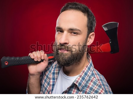 Confident, brutal bearded man with big axe on a red background.