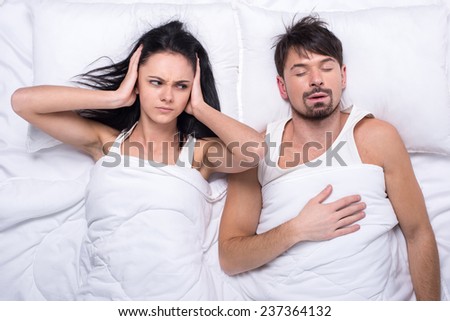 Angry woman is trying to fall asleep while man is snoring.