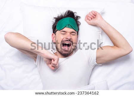 Top view of young sleepy man with sleep mask in the bed.
