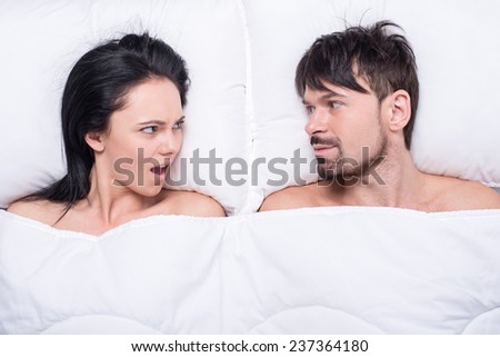 Young happy couple in a bed. Top view. They are looking at each other.