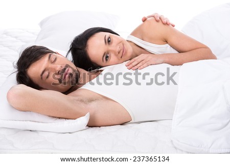 Young happy couple in a bed. Isolated on white background.