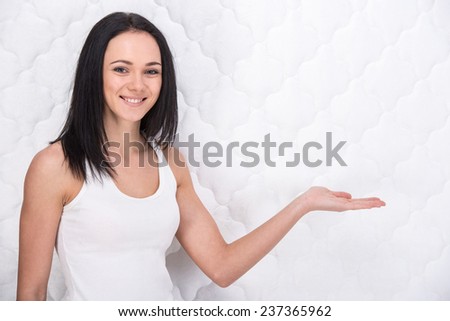 Smiling young woman with orthopedic mattress. Quality mattress.