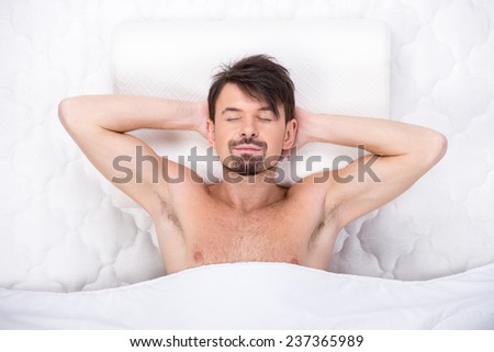 A young man is sleeping on a mattress. Top view. Isolated on white background