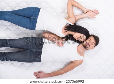 Young couple is lying on the mattress. Top view.