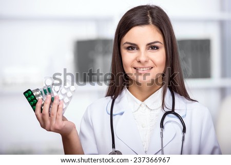 Smiling, beautiful medical doctor woman in medical room with pills.