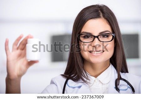 Smiling, beautiful medical doctor woman in medical room with pills.