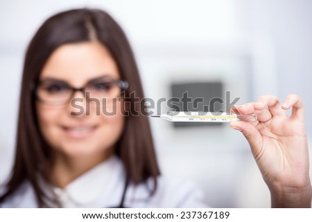 Young beautiful woman doctor with thermometer. Focus on the thermometer.