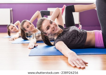 Group of active smiling women are training in fitness club. Smiling and looking at the camera.