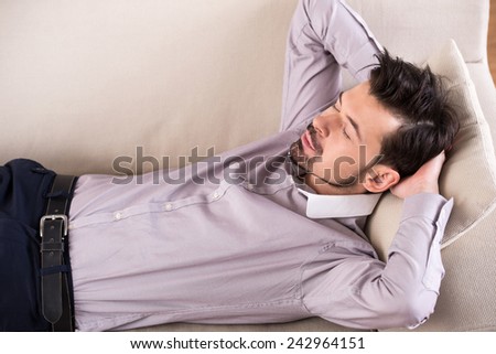 Tired businessman is sleeping on the sofa at the office.
