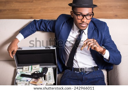Young black man is wearing suit and hat with gun and money.