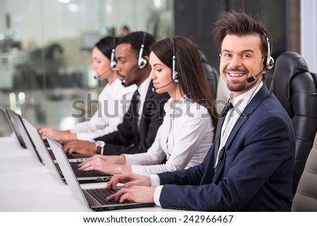 Side view of line of call centre employees are smiling and working on computers.