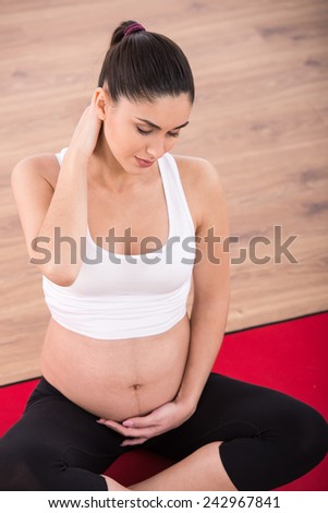 Top view of beautiful, smiling pregnant woman, while she is doing exercises.