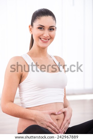 Pregnant woman, concept heart on stomach. Hands forming heart on female belly button.