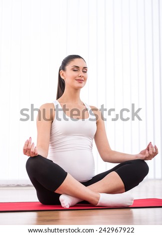 Prenatal yoga. Pregnant woman is  doing yoga exercise on a white background.