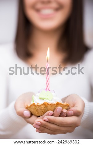 Close-up of birthday cake. Young woman is holding cake with candle.