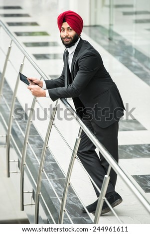 Young indian businessman in modern office with tablet.