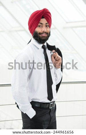 Young indian businessman in suit and turban is smiling while looking at the camera.