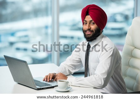 Smiling indian businessman is working on his computer in the office.