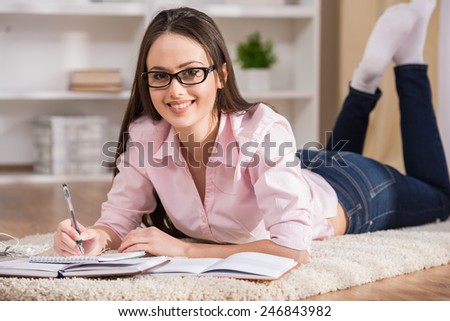 Education and home concept. Smiling student girl is reading books at home.