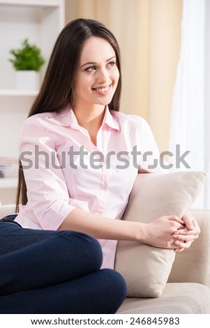 Side view of beautiful woman is siting on sofa.