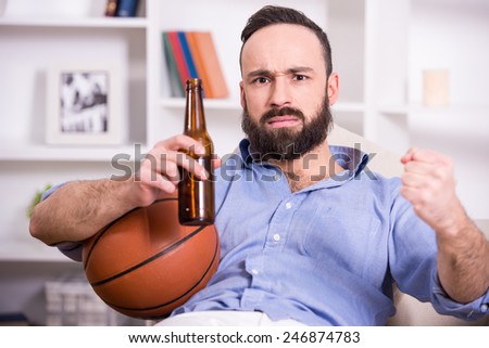 Young man with basketball and beer while watching the game.