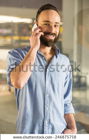 Businessman is talking by phone, seen through glass in the living room at home.
