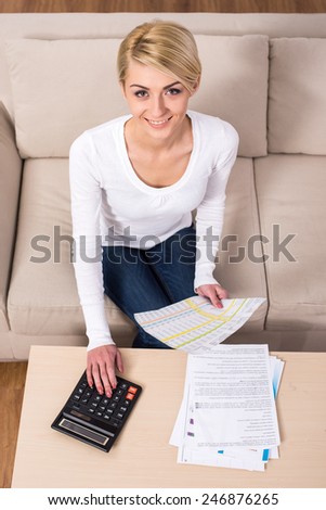 Business planning, young woman is checking bills and doing budget with calculator, computer and papers in fashion design studio. Top view.
