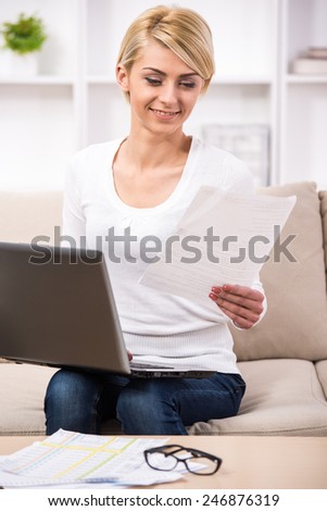Business planning, young woman is checking bills and doing budget with calculator, computer and papers in fashion design studio.