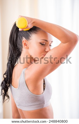 Young woman is exercising with dumbbells at home. Fitness, workout, healthy living and diet concept.