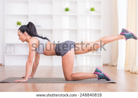 Pretty woman is doing fitness at home on her living room floor. Fitness, workout, healthy living and diet concept.
