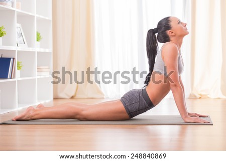 Pretty woman is doing fitness at home on her living room floor. Fitness, workout, healthy living and diet concept.